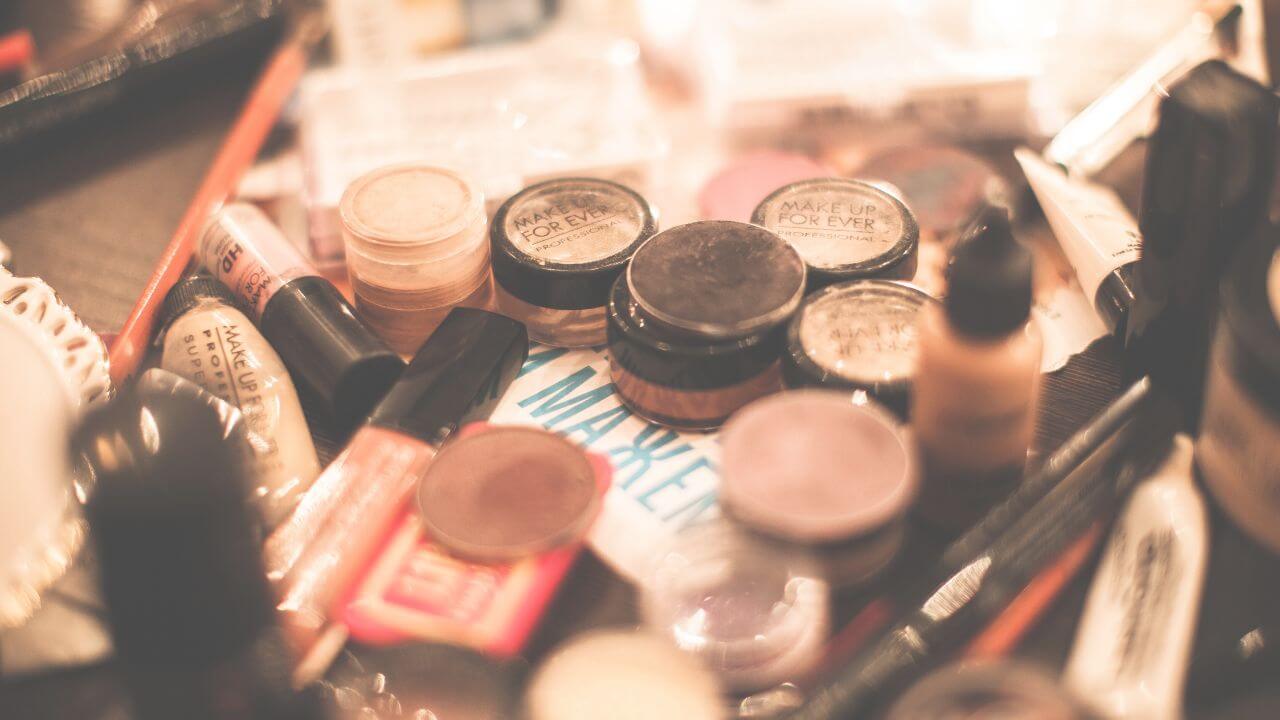 A variety of used makeup products and tools scattered across a messy makeup table.